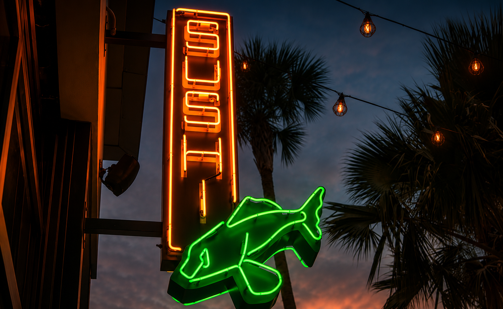 Neon sushi sign glowing above palm trees outside Garage in Coconut Grove